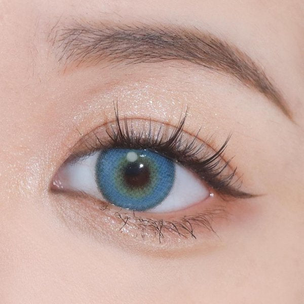 Close-up image of an eye wearing Say Yes Very Blue lenses, showcasing vivid blue tones with soft yellow accents for a natural, mesmerizing effect.