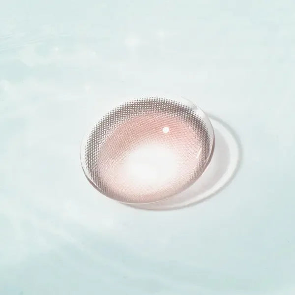 Caramel Pink Chic contact lens with soft pink hues, displayed on a reflective surface, ideal for a natural and chic eye enhancement.