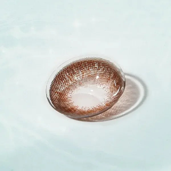Neo Dali Extra Brown contact lens with warm brown design, displayed on a reflective surface for a natural and defined eye look.