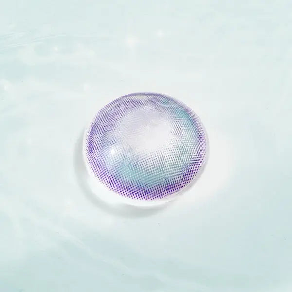 Metafantasia Blue contact lens with blue and purple design, displayed on a reflective surface for a striking eye enhancement.