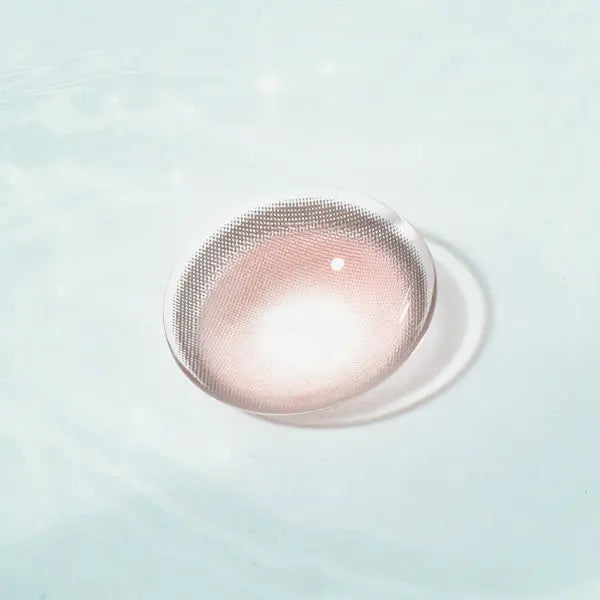 Caramel Pink Chic contact lens with soft pink hues, displayed on a reflective surface, ideal for a natural and chic eye enhancement.