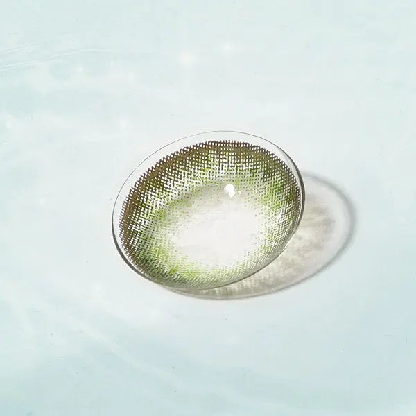 Neo Dali Extra Green contact lens on a reflective surface, showcasing a detailed pattern and bold green tone for standout eyes.