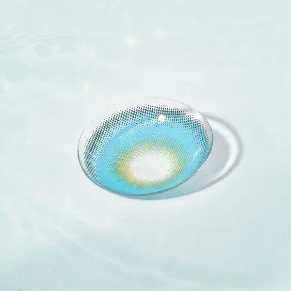A single Say Yes Very Blue lens placed in water, revealing its blue gradient with yellow details in the design.